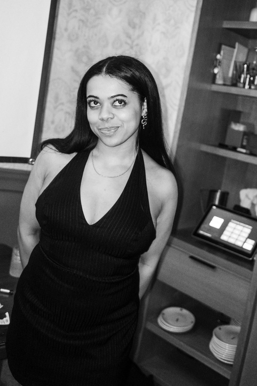 guest in a halter dress smiling by the shelves
