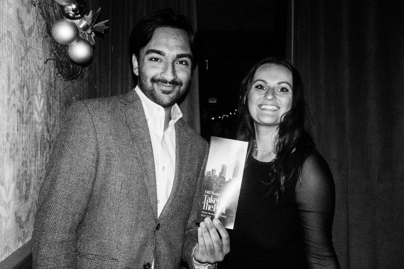 two guests smiling and holding up the printed program