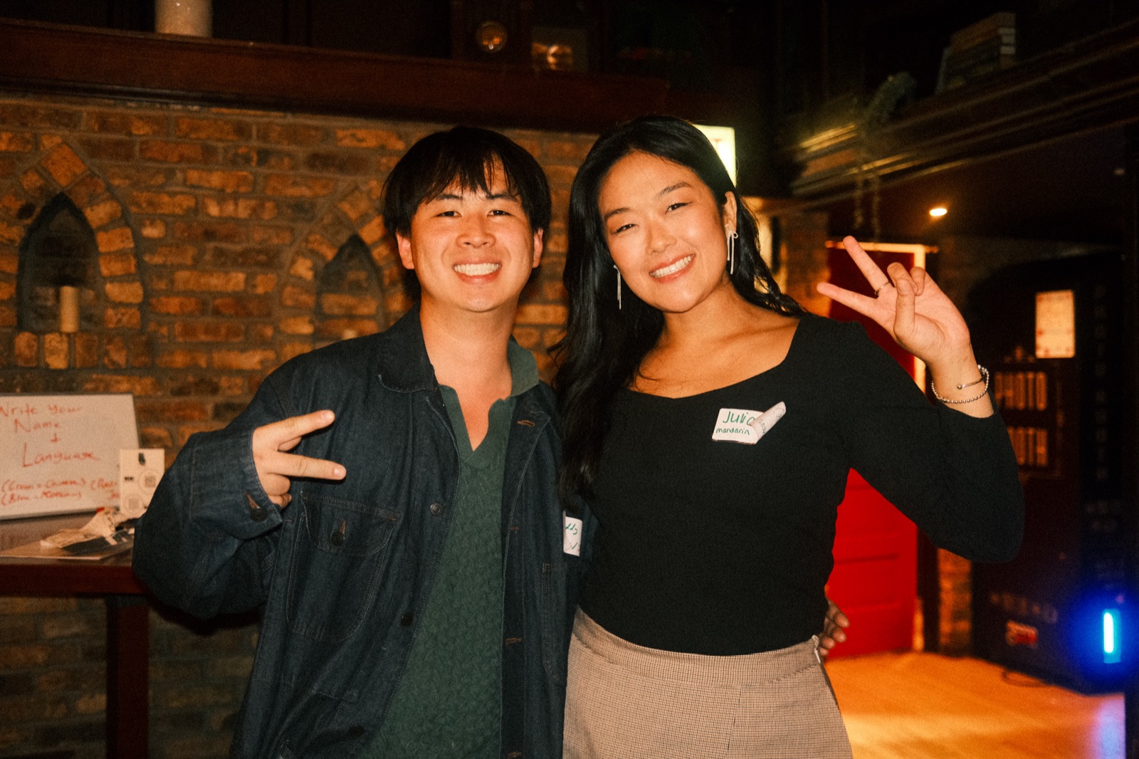 the hosts beside the write-your-name-and-language sign at the door
