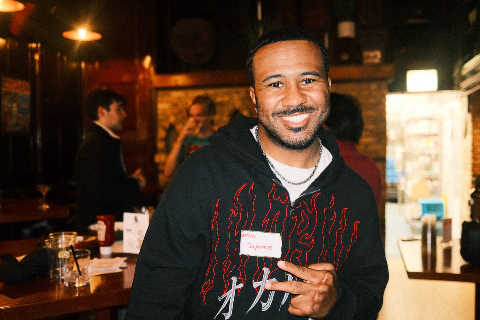 a guest grinning while holding up his name tag — learning japanese