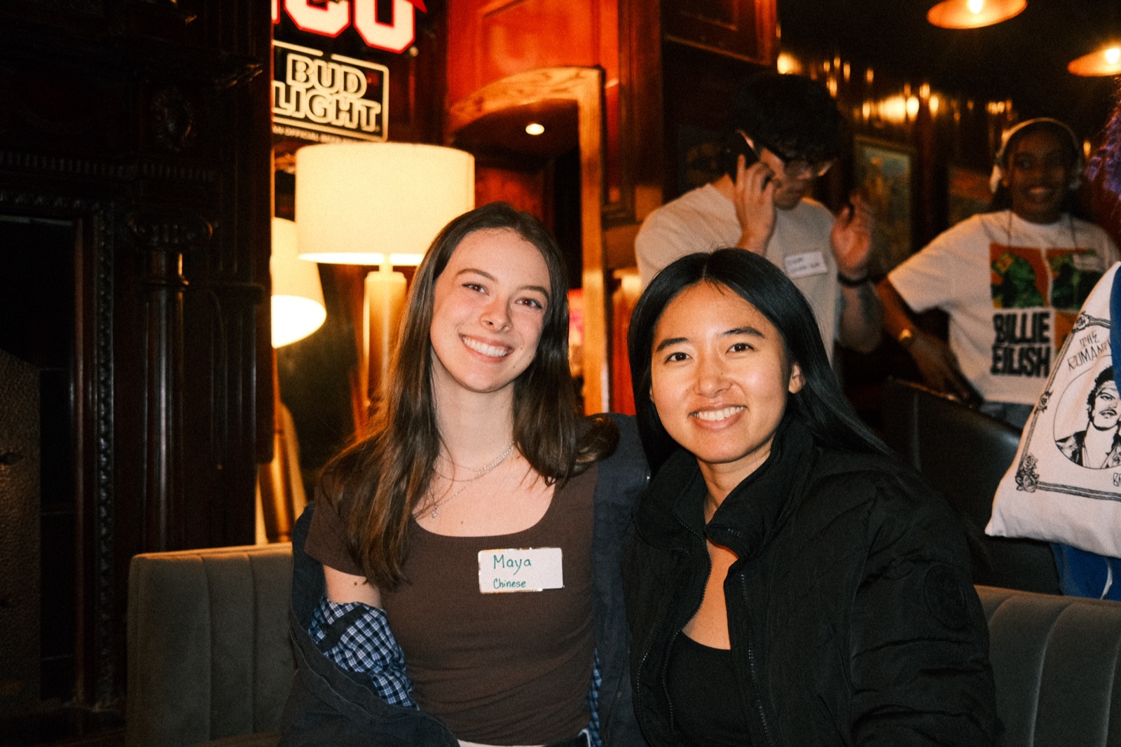 two friends beaming, a name tag reading chinese between them