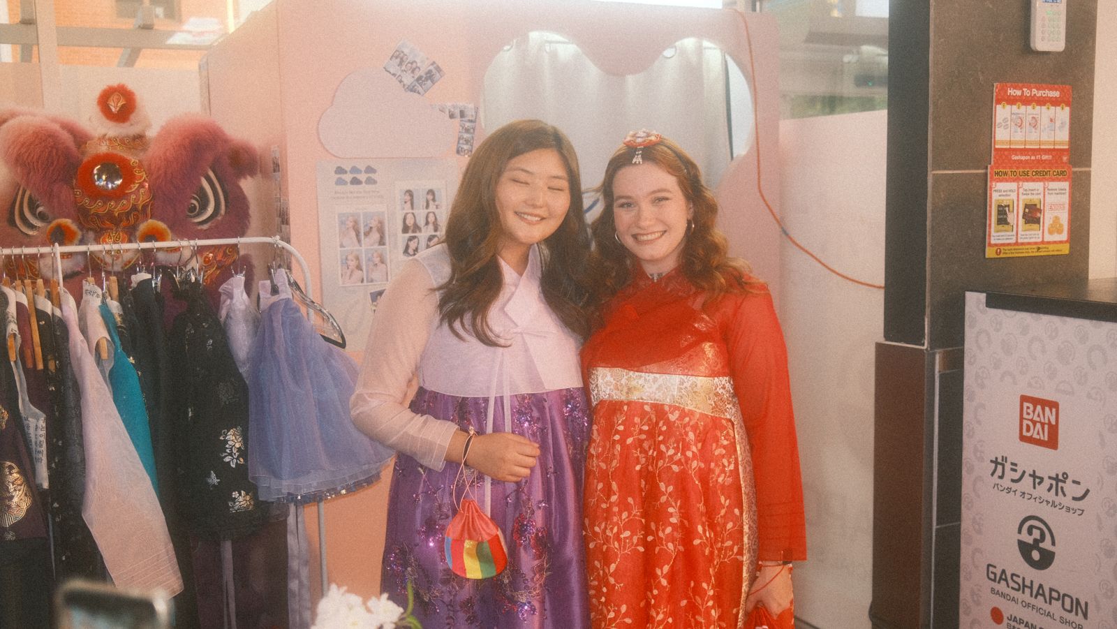 two guests trying on hanbok beside the lion dance heads