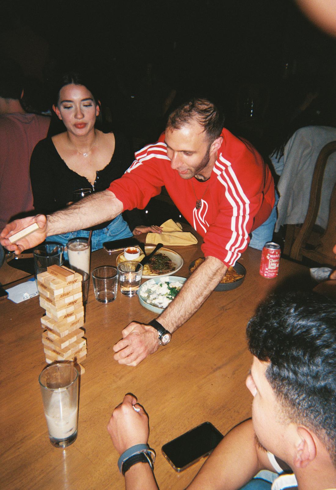 reaching over a teetering jenga tower at the board-game cafe social