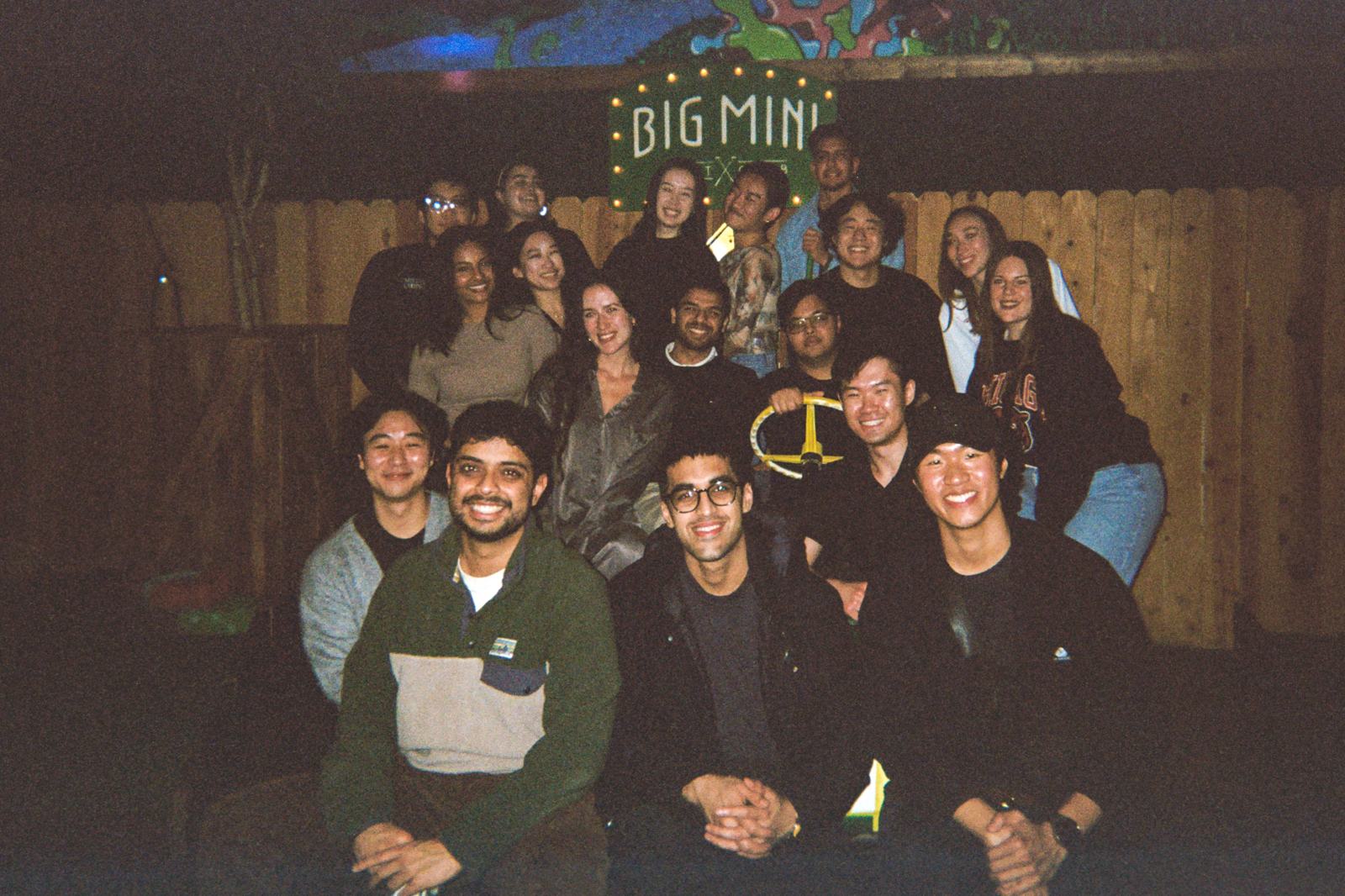 the whole crew packed under the big mini neon sign at the member reunion